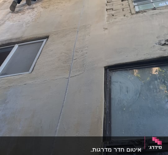 עבודת איטום בסנפלינג על קיר חיצוני וחלונות בבניין מגורים